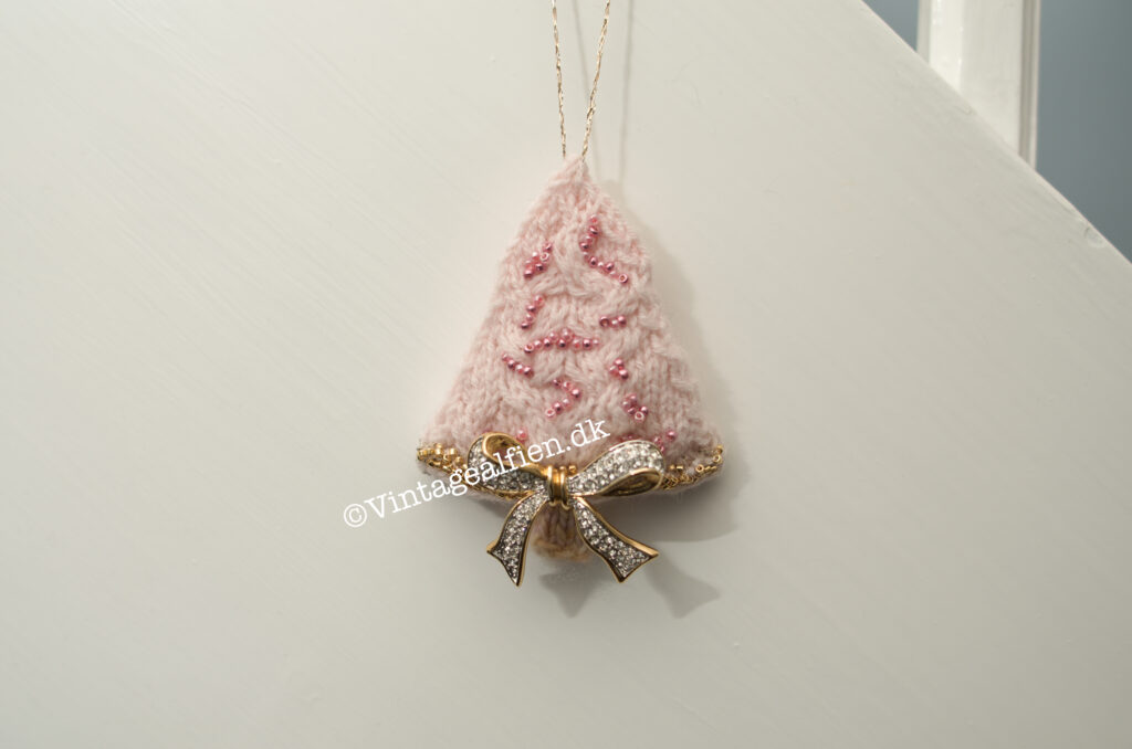 De strikkede juletræer - Et strikket juletræ med små snoninger påsyede perler og en sløjfebroche